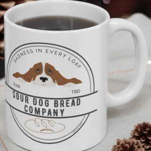 White Mug with the image of a sad dog and the saying, "Sour Dog Bread Company."