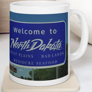 White Mug with fake state motto for North Dakota: Great Plains, Bad Lands, Mediocre Seafood."